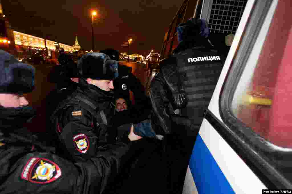 Задержанного гражданского активиста вносят в полицейский автобус