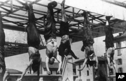 Тела Бенито Муссолини, Клары Петаччи и еще нескольких фашистских лидеров, повешенные за ноги на Пьяццале Лорето в Милане, 28 апреля 1945 года