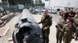Israeli military spokesman Rear Admiral Daniel Hagari (C) and other members of the Israeli military stand next to an Iranian ballistic missile which fell in Israel on the weekend, during a media tour at the Julis military base near the southern Israeli ci