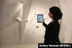 Сотрудница российского павильона показывает, как смотреть на инсталляцию через айпад