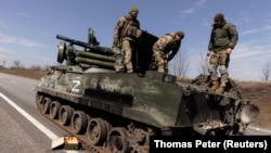 Украинские солдаты на подбитом танке российской армии. Март 2022 г.