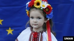 Девочка в национальном костюме на фоне флага Евросоюза во время празднования Дня независимости Украины в Киеве