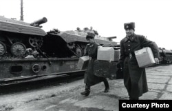 Советские военные грузят на поезд танки и амуницию