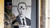 Боец Территориальной обороны Украины и мишень с изображением президента России Владимира Путина во время военной подготовки недалеко от Киева, 20 мая 2022 года 
