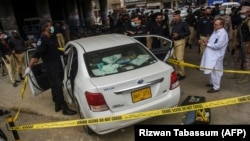 Investigators examine the scene where gunmen opened fire on two Chinese workers in Karachi on July 28. 