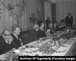 Tito and companions, including his wife Jovanka, roar with laughter during a speech at a dinner party.