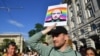 Участник акции протеста против венгерского закона об "ЛГБТ-пропаганде" держит в руке плакат с изображением Владимира Путина на фоне радужной символики. Будапешт, июнь 2021 года