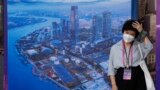 Một phụ nữ mang khẩu trang đứng gần một bảng quảng cáo thành phố Thượng Hải, ngày 6/7/2023. Trung Quốc báo cáo trong tháng Sáu có 239 người thiệt mạng vì COVID.
