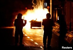 FILE - Polisi anti huru hara berdiri di samping kendaraan polisi yang terbakar, di dekat lokasi dugaan penikaman yang menyebabkan beberapa anak terluka di Dublin, Irlandia, 23 November 2023. (REUTERS/Clodagh Kilcoyne)