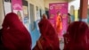 Women wait to cast their votes as one of them stands behind a selfie point during the first round of voting of India's national election in Behror, Rajasthan state, India, April 19, 2024.