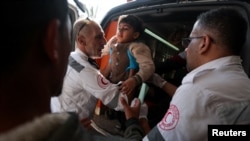 4 دسمبر 2023 کو جنوبی غزہ کی پٹی کے خان یونس میں، اسرائیلی حملوں کے بعد فلسطینی ہلال احمر سوسائٹی کے ارکان ایک فلسطینی بچے کی مدد کر رہے ہیں جب زخمی فلسطینیوں کو ناصر ہسپتال منتقل کیا جا رہا ہے۔ 