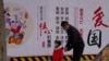 一名男子帶著小女孩走過北京街頭一面中國政府的宣傳社會主義核心價值觀的宣傳牆。（2021年3月7日）