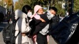 一名男子背着一个女孩离开北京的一所儿童医院。(2023年11月24日)