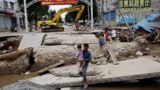 FILE - A man holding a child walks across a damaged bridge after rains and floods brought by remnants of Typhoon Doksuri, in Zhuozhou, Hebei province, China August 7, 2023. (REUTERS/Tingshu Wang)