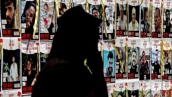 A person walks past posters of Israeli hostages held in Gaza since the October 7 attacks by Palestinian militants, during a protest by the families of the hostages and their supporters, in Tel Aviv on April 25, 2024.