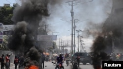 Waendesha piki piki wakipita karibu na moto uliowashwa na waandamanaji mjini Port-au-prince, Haiti, March 7, 2024 PICHA: Reuters