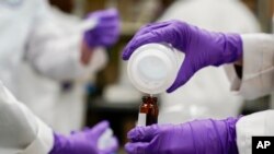 FILE - Water researcher Eva Stebel pours a water sample into a container for experimentation as part of a research at the Environmental Protection Agency Center for Environmental Solutions and Emergency Response, Feb. 16, 2023, in Cincinnati. 