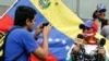 ARCHIVO - Un hombre toma una fotografía de una mujer que, mientras sostiene micrófonos, lleva una mordaza y una cadena. Fue durante una manifestación para conmemorar el día Mundial de la Libertad de Prensa en Caracas, Venezuela, el 3 de mayo de 2016.