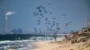 (FILE) An aircraft airdrops humanitarian aid over the northern Gaza Strip, as seen from central Gaza, March 25, 2024. 