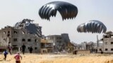 FILE—People rush to landing humanitarian aid packages dropped over the northern Gaza Strip on April 23, 2024.