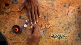 A voter puts his hand on a classroom desk covered in marks as a polling officer applies an indelible ink mark on his index finger at a polling station inside a school, near Palakkad, in Indian southern state of Kerala.