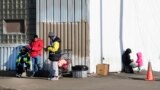 FILE - Immigrants stand outside a shelter in the Pilsen neighborhood of the city of Chicago, Illinois, Dec. 19, 2023. Across Chicago, Black residents are frustrated that their long-standing needs are not being met while the needs of the city's newly arrived are met with urgency.