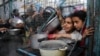 غزہ کی پٹی میں کھانا تقسیم کرنے کی ایک تنظیم کے باہر بچے اپنی باری کا انتظار کر رہے ہیں۔ 18 مارچ 2024