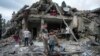 FILE - Palestinians look at the destruction after an Israeli airstrike in Deir al Balah, Gaza Strip, April 30, 2024.