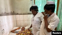 FILE - Nurses talk with a 13-year-old boy with a gunshot wound as he lies in a hospital bed in Kumba, Cameroon, Oct. 25, 2020.