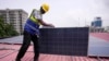 FILE - Oladapo Adekunle, an engineer with Rensource Energy, installs solar panels on a roof of a house in Lagos, Nigeria, March 21, 2024. 