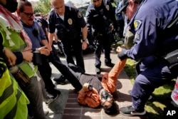 A University of Southern California protester is detained by USC Department of Public Safety officers during a pro-Palestinian occupation at the campus' Alumni Park in Los Angeles, California, April 24, 2024.