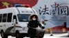一輛警車和一名女子騎車駛過北京街頭一堵宣傳中國法治的宣傳牆。（2016年12月28日）