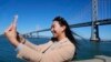 Content creator Cynthia Huang Wang works below the San Francisco-Oakland Bay Bridge in San Francisco, April 8, 2024. 