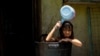 Children take a bath in a bucket during a hot day in Manila, Philippines.