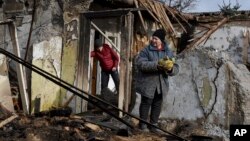 A woman holds food items found as she stands outside her house which was destroyed by a Russian drone attack in a residential neighborhood, in Zaporizhzhia, Ukraine, on March 28, 2024.
