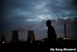Seorang pria berjalan melewati pembangkit listrik tenaga batu bara di kota Shanghai, China (foto: dok).