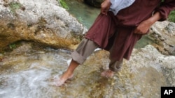 FILE - A person walks in a fountain, once used by local residents as drinking water, in the Alborz mountains close to Chalandar village, north of Tehran, Iran. A U.N. report lists Iran as one country experiencing very high stress levels over water.