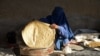 یک زن افغان که چادری به سر دارد، در یکی از نانوایی‌های ولایت قندهار نان‌پزی می‌کند و آنرا در مارکیت این شهر می‌فروشد (تصویر از آرشیف صدای امریکا)