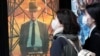 People walk by a poster to promote the movie "Oppenheimer" March 29, 2024, in Tokyo. 