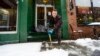 Mikey Reynolds, an employee at The Works on Main Street in Brattleboro, Vt., shovels the sidewalk in front of the restaurant as a person sleeps in the doorway on March 23, 2024. 