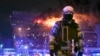 Un militaire russe de la Garde nationale sécurise une zone alors qu'un incendie massif est observé au-dessus de l'hôtel de ville de Crocus, à Moscou, en Russie, le vendredi 22 mars 2024. ((AP Photo/Dmitry Serebryakov)