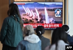 22일 북한 비공개 장소에서 진행된 핵반격가상종합전술훈련 중 방사포가 발사되는 모습을 한국 서울역에서 시민들이 시청하고 있다.