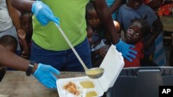 FILE - A server ladles soup into a container as children line up to receive food at a shelter for families displaced by gang violence, in Port-au-Prince, Haiti, March 14, 2024.