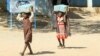 FILE - Children carry packs of humanitarian aid at a school housing displaced Sudanese who had fled violence in their war-torn country, near Gedaref, March 10, 2024. The majority of those fleeing the war in Sudan are under age 18.