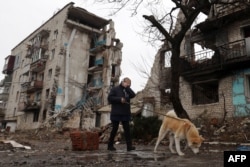 Жительница Изюма выгуливает собаку среди руин города