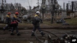 (FILE) Power plant workers walk to repair damages after a Russian attack in central Ukraine.