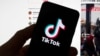 FILE - The TikTok logo is seen on a mobile phone in front of a computer displaying the TikTok home screen, in Boston, March 18, 2023.