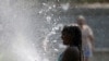 ARCHIVO - Una niña se refresca en una fuente en Madrid, durante la segunda ola de calor del año. 