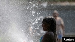 ARCHIVO - Una niña se refresca en una fuente en Madrid, durante la segunda ola de calor del año. 