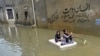 Girls use a temporary raft across a flooded street after heavy monsoon rains in Karachi, Pakistan.
